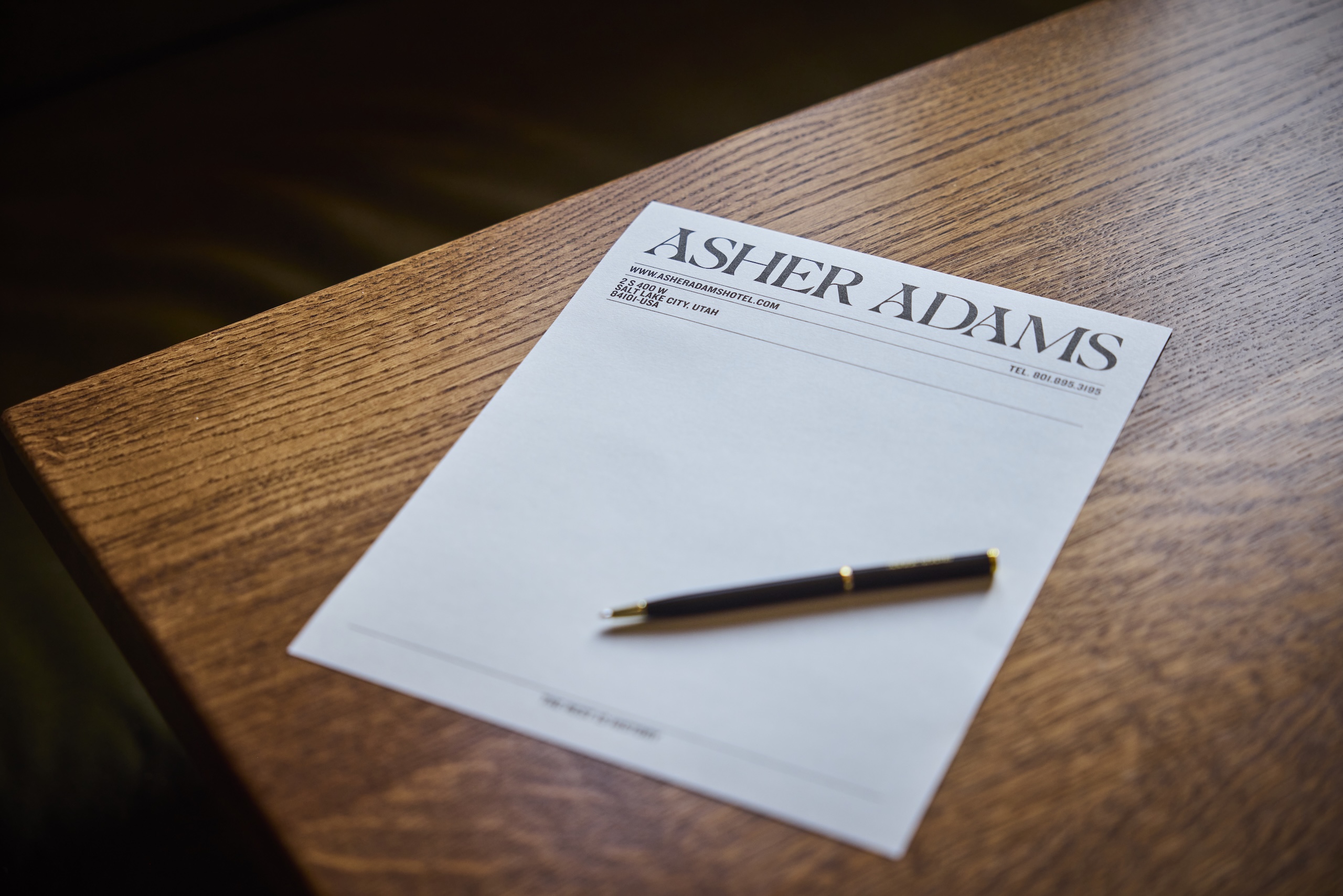 Asher Adams stationary and pen on a wooden table