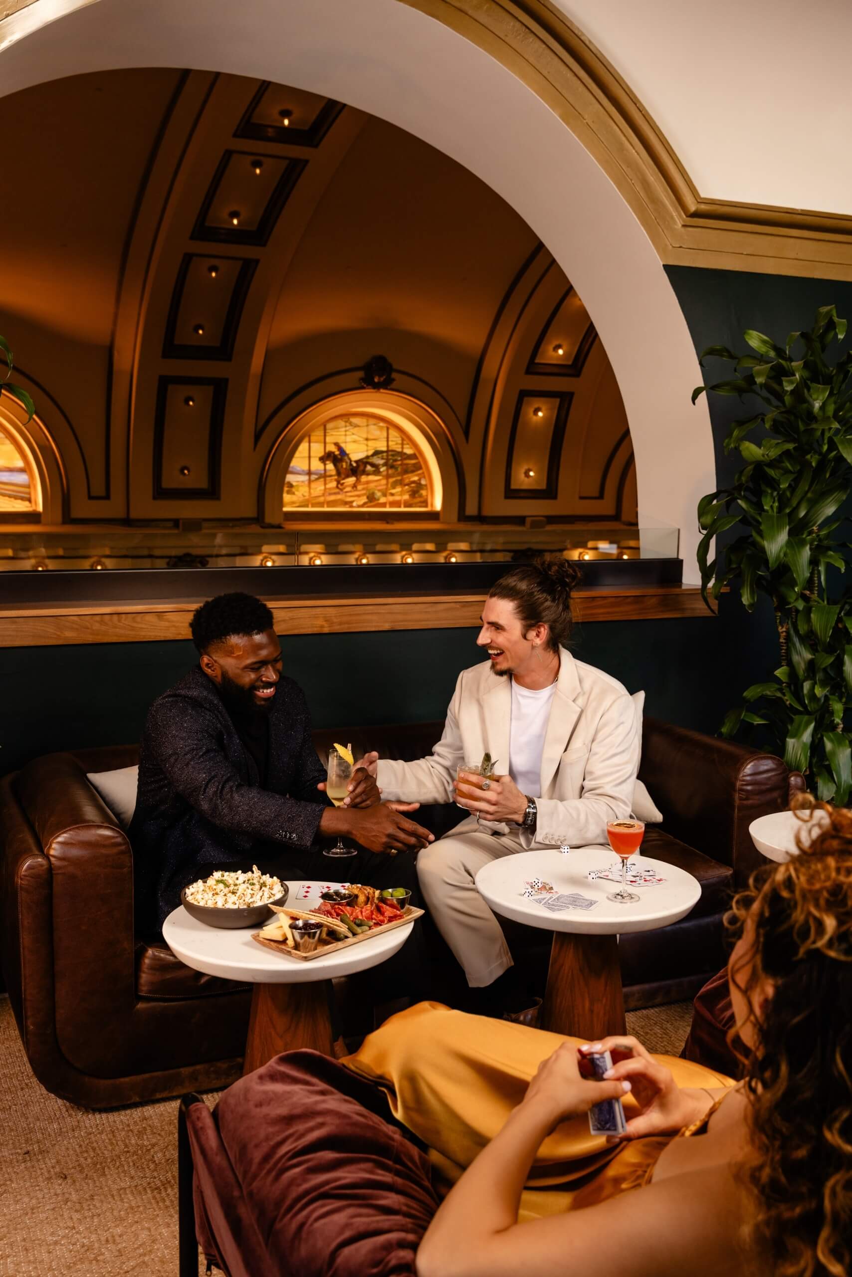 Two men having snacks and cocktails on couch in No. 119